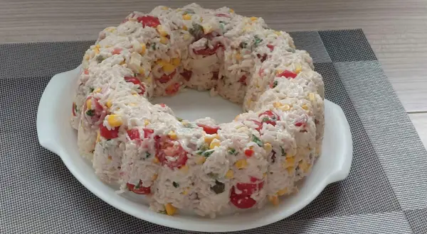 Salade de riz en forme de couronne, garnie de tomates cerises, maïs et persil.