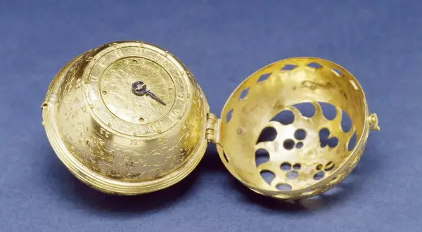 Esfera dorada ornamentada de un primer reloj mecánico, abierta para mostrar su intrincado interior.