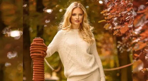 Kobieta w swetrze w stylu scandi, otoczona jesiennymi liśćmi.