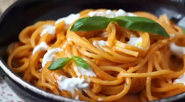 Spaghetti med krämig tomatsås och burrata, toppad med färsk basilika. En härlig pasta burrata-rätt.