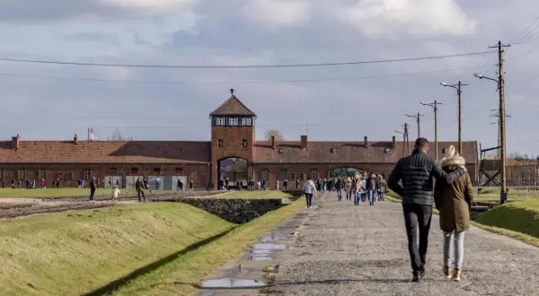 Spacer po terenie Państwowego Muzeum Auschwitz-Birkenau w Oświęcimiu. Ludzie zwiedzają teren byłego obozu.