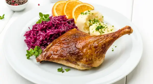 Pieczona kaczka z purée, czerwoną kapustą i pomarańczą. Marynata do kaczki nadała jej apetyczny, złocisty kolor.