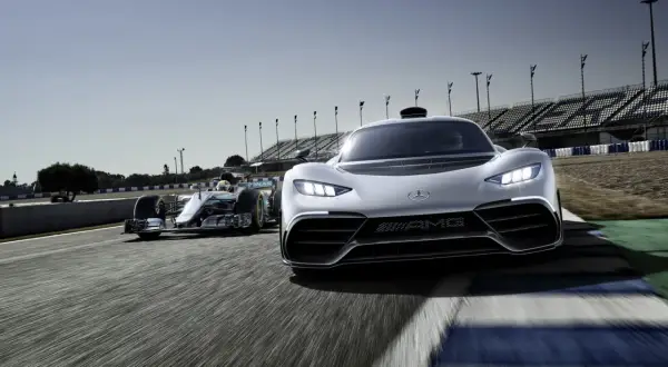 Wyścigowy bolid F1 i biały Mercedes-AMG Project One pędzą po torze.