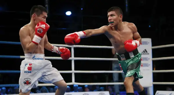 Two boxers exchange blows, showcasing advanced boxing techniques. One fighter throws a jab while the other defends, both wearing red gloves.