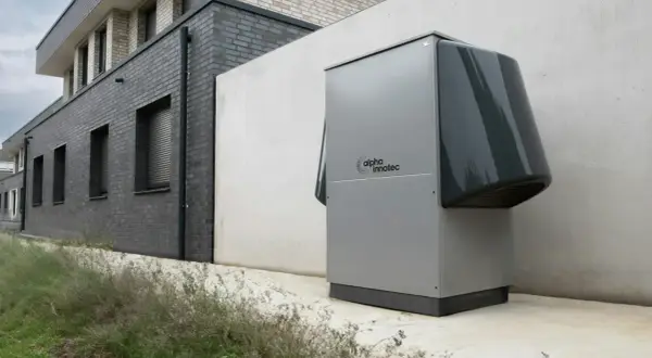 Une pompe à chaleur Alpha Innotec est installée près d'un bâtiment moderne. Elle fonctionne pour réguler la température, mais combien de temps tourne une pompe à chaleur par jour ?