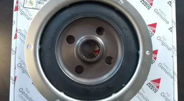 Metalowy tłumik drgań skrętnych z gumowym elementem, częścią AGCO Parts.
