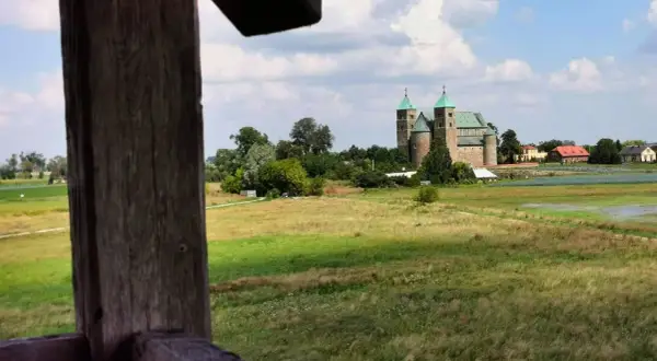 Wnętrze kolegiaty z rzędami drewnianych ławek i witrażami w oknach.