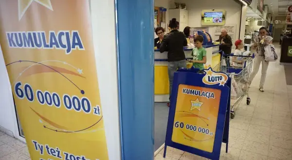 Baner i stojak reklamowy Lotto z informacją o kumulacji 60 milionów złotych.