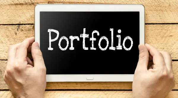 Ręce trzymają tablet z napisem "Portfolio". Szukasz e-portfolio przykłady?