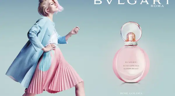 Kobieta w pastelowej stylizacji obok flakonu perfum Bvlgari Rose Goldea Blossom Delight.
