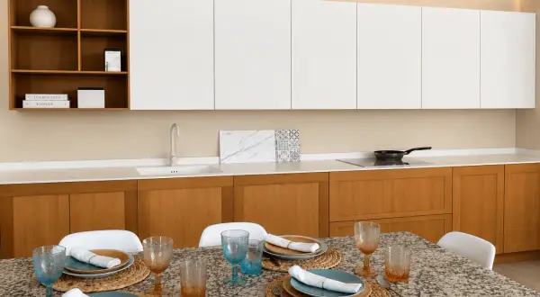 Elegantes cocinas modernas blancas con gabinetes de madera, encimera de cuarzo y mesa lista para cenar.