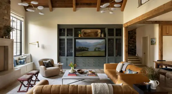 Cozy living room in a ranch style house featuring leather sofas, a stone fireplace, and a built-in entertainment center with a landscape painting.