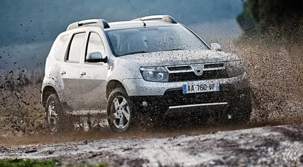 Srebrny Dacia Duster pruje przez błoto, pokazując, że to jedne z **aut tanich w utrzymaniu**, gotowe na każdą przygodę.