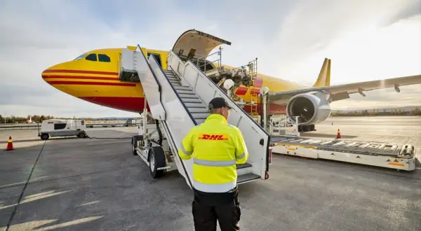 Pracownik DHL nadzoruje załadunek przesyłki lotnicze do samolotu.