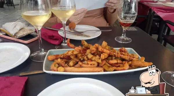 Tapas y copas de vino en el bar La Cala Almería. Un plato de patatas fritas con salchichas y una cerveza acompañan la comida.