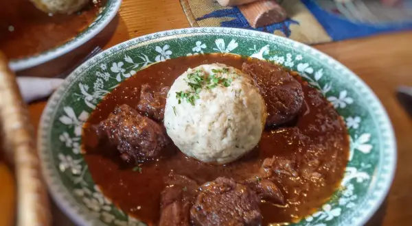 Herzhaftes Gulasch mit Klößen, ein klassisches Gulasch Rezept, serviert auf einem Teller mit grünem Muster.