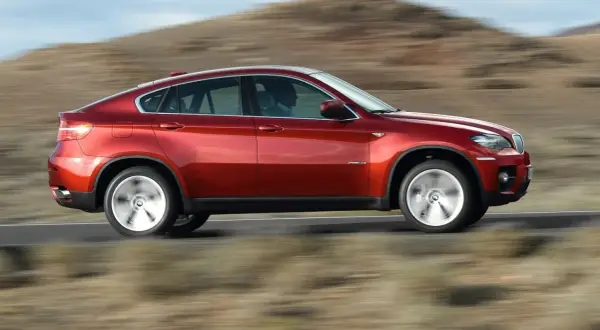 Czerwony BMW X6 pędzi po pustynnej drodze. Oto moto!