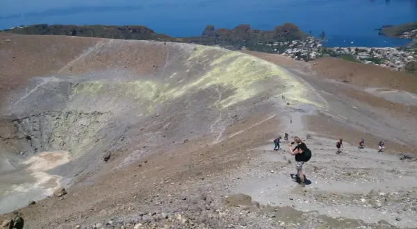 Une randonnée en Sicile sur un volcan actif, avec des sentiers rocailleux et une vue sur la mer et un village.