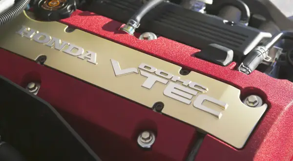 Złota pokrywa silnika Honda z napisem VTEC. Czerwone, teksturowane wykończenie dodaje sportowego charakteru.