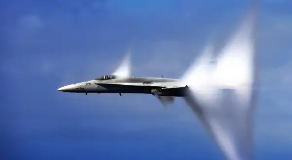 Myśliwiec F/A-18 Super Hornet przekracza barierę dźwięku, tworząc stożki kondensacji. Niesamowita prędkość samolotu w akcji.