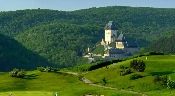 Burg Karlštejn thront majestätisch über einer grünen Golflandschaft.