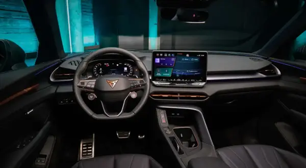 Interni moderni e tecnologici della Cupra Terramar, con ampio display centrale, volante sportivo e illuminazione d'ambiente.