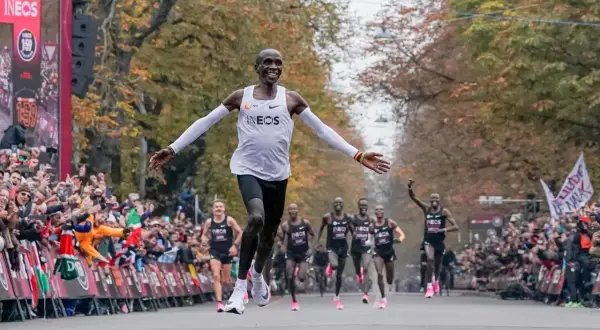Eliud Kipchoge przekracza linię mety, ustanawiając nowy maraton rekord świata. Tłumy wiwatują, widząc historyczny bieg.