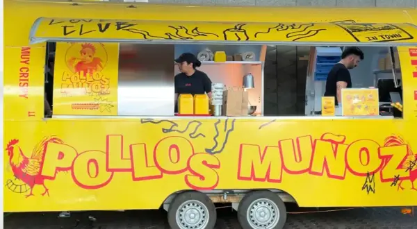 Camión amarillo "Pollos Muñoz" con un gallo rojo. Dos empleados trabajan en el interior.