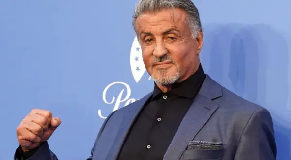Sylvester Stallone, gwiazda wielu kultowych filmów, pozuje z zaciśniętą pięścią.