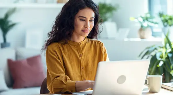 Femme concentrée sur son ordinateur portable, effectuant une recherche sur la naissance d'une personne.