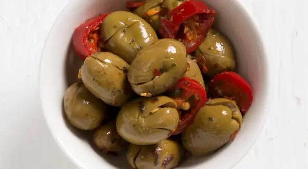 Olive verdi schiacciate con peperoncino rosso in una ciotola bianca. Perfette per un antipasto veloce, ecco come fare le olive verdi schiacciate.