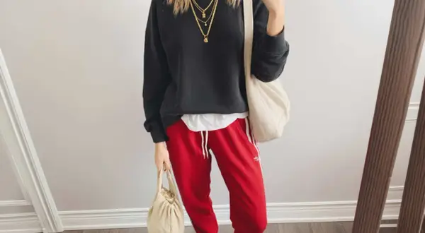 Styling-Idee: Schwarzer Pullover, weiße Schicht, rote Hose mit weißen Streifen, Leo-Sneaker und cremefarbene Taschen. Perfekt, wenn du fragst, was passt zu roter Hose!