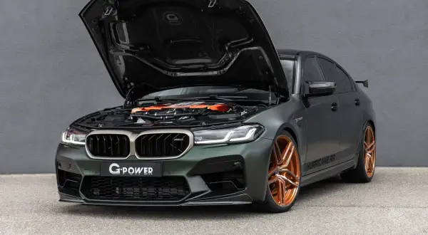 Mocarny BMW M5 G Power z otwartą maską, prezentujący pomarańczowy silnik i miedziane felgi.