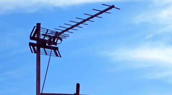 Antena naziemna do odbioru sygnału DVB-T na tle błękitnego nieba z chmurami.