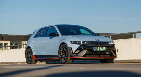 Sportowy Hyundai Ioniq 5 N w kolorze jasnoszarym z czerwonymi akcentami, zaparkowany na zewnątrz.