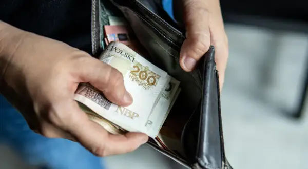 Ręce wkładają polskie banknoty do portfela. Czy to wystarczy na pensję minimalną 2026?