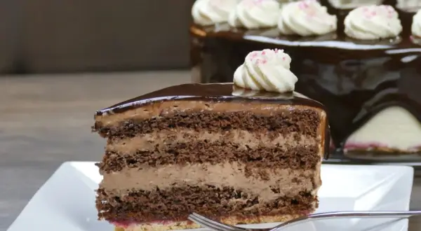 Ein Stück saftige Schoko Sahne Torte mit glänzendem Schokoladenguss und zarter Sahnehaube.