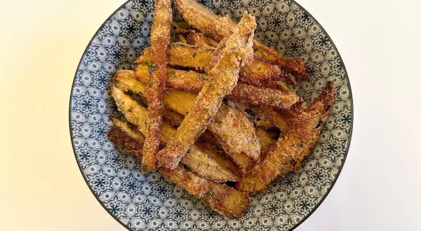 Bastoncini di melanzane impanate, un classico delle ricette della nonna, serviti in una ciotola decorata.