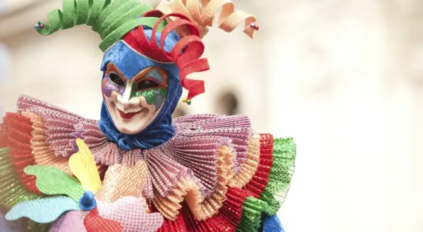 Maschera colorata con cappello a spirale, un costume da giullare che evoca la gioia del carnevale, una festa pagana di travestimenti e allegria.