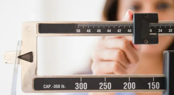 Bilancia meccanica con una mano che regola il peso. La scala mostra numeri come 50, 48, 46, 44, 42, 40, 36, 34, 32, 300, 250, 200, 150. Forse la persona sta pensando che le more fanno ingrassare.