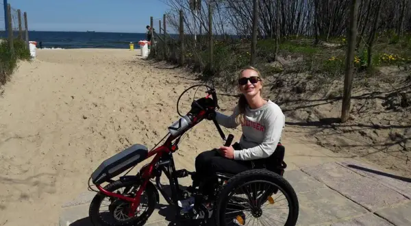 Kobieta na wózku inwalidzkim z napędem elektrycznym na plaży.