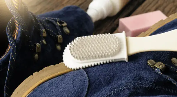 Pflege für deine leguano schuhe: Blaue Wildlederschuhe werden mit einer Bürste und Pflegeprodukten gereinigt.