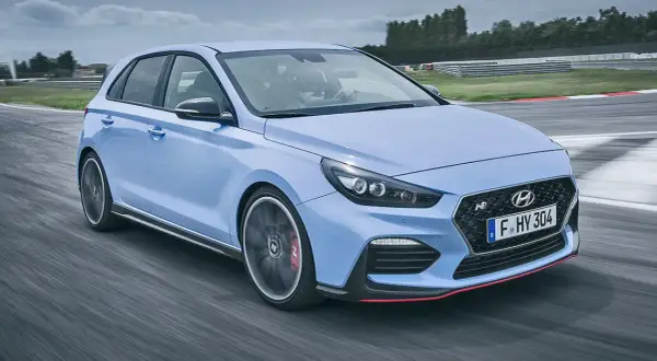 Un Hyundai i30 N azul compite en una pista, mostrando su potente motor y diseño deportivo.