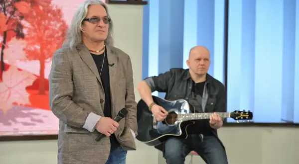 Mężczyzna z mikrofonem i długimi włosami, obok niego siedzi drugi mężczyzna grający na gitarze. Może to być idealny tekst kołysanki dla nieznajomej.