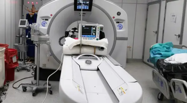 Nowoczesny aparat do badania tomografem w gabinecie diagnostycznym. Obok stoi łóżko pacjenta.