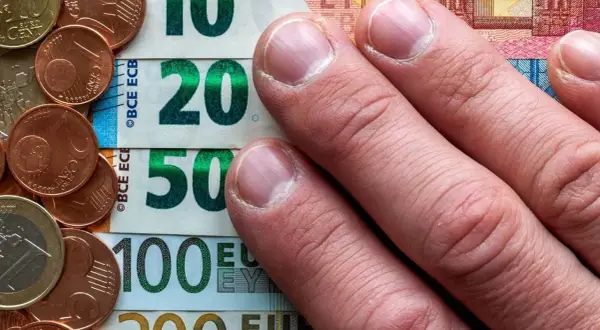 Dłonie na banknotach 10, 20, 50, 100 euro i monetach. To archiwum kursu euro.