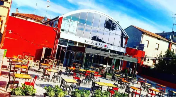 Birrificio Renton, una moderna hilltop brewery con tavoli all'aperto sotto un cielo azzurro.
