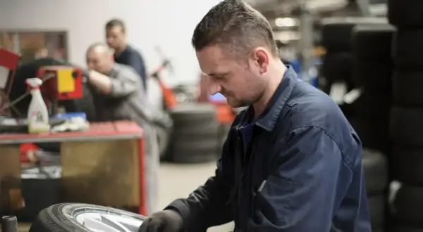 Mechanik w warsztacie naprawia oponę samochodową.