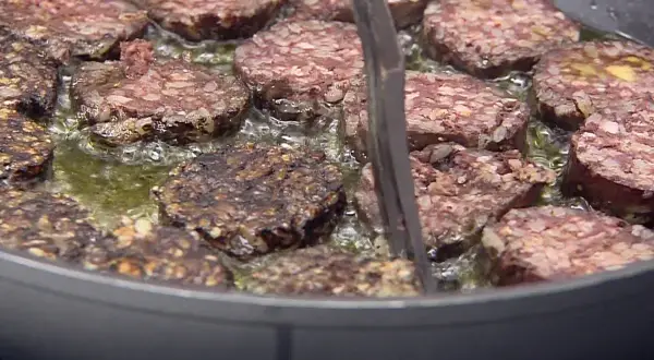 Rodajas de morcilla de Burgos dorándose en sartén con aceite burbujeante. Perfectas para tus recetas.