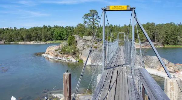 Hängbro över vatten med skogklädda öar. Perfekt för en utflykt Stockholm.